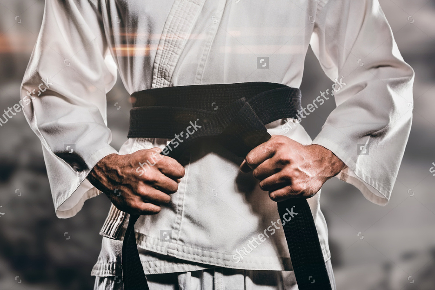 stock-photo-fighter-tightening-karate-belt-against-rock-crashing-down-from-cliff-434160028